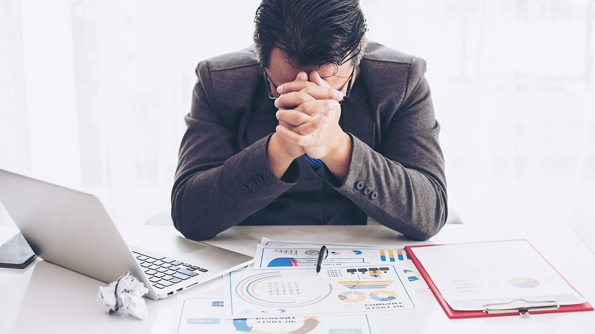 man putting his head down from stress at work